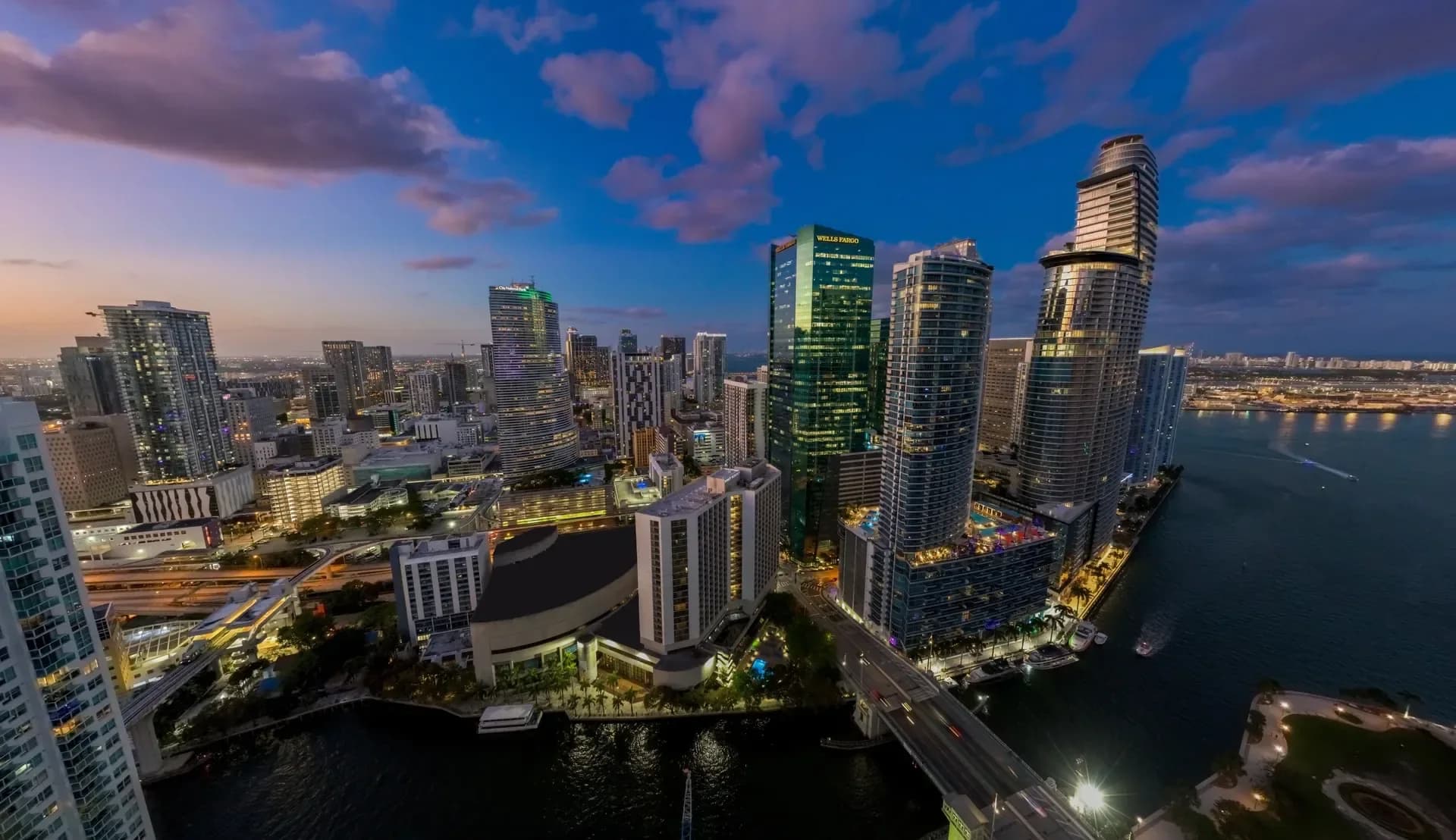 Aerial view of Brickell at dusk, with the Miami River and Biscayne Bay